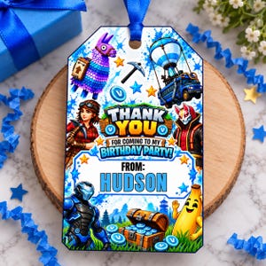 Peut inclure: Une étiquette cadeau rectangulaire avec un ruban bleu illustrée de personnages Fortnite, dont un lama, un bus de combat et une banane. Le texte indique : THANK YOU FOR COMING TO MY BIRTHDAY PARTY! FROM: HUDSON. Le design inclut des éclaboussures bleues.