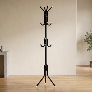 May include: A tall, black metal coat rack featuring a central vertical pole supported by three curved legs at the base. It includes multiple tiers of hooks for hanging items, each finished with small white caps at the ends of the metal arms.