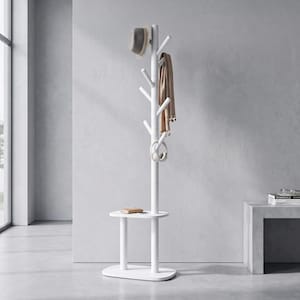 May include: A white floor-standing coat rack featuring a central vertical pole with multiple angled hooks, a small integrated oval shelf, and a flat oval base. A grey fedora, a tan scarf, and white headphones are hanging from the hooks.