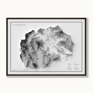 Peut inclure: Une carte topographique en noir et blanc de la Macédoine du Nord encadrée, présentant un relief ombré détaillé. L'impression comprend une échelle graphique, des données techniques et les altitudes maximale et minimale dans un cadre en bois sombre.