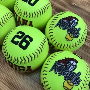 May include: Five yellow softball with brown stitching.  Three of the softballs have a black number, 20, 26, and 20. Two of the softballs have a brown embroidered logo that says "Knights".
