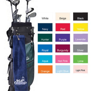 May include: A black golf bag with a green pocket and a blue towel hanging from the side. The towel has the text "BGA INSURANCE" and a lighthouse graphic. The bag is filled with golf clubs.