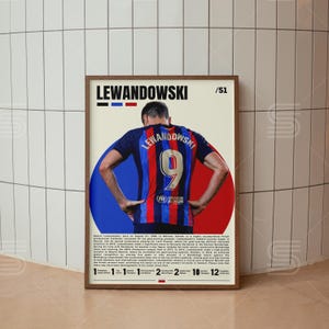 May include: A framed poster featuring a footballer wearing a blue and red striped jersey with the name LEWANDOWSKI and the number 9 on the back. The design includes a circular background, text biography, and a list of career achievements.