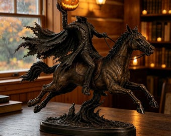 May include: A bronze-toned sculpture of a headless rider on horseback, wearing a tattered cloak and holding a glowing, lit jack-o'-lantern pumpkin aloft. The figure is mounted on a dark oval base, capturing a dynamic pose with the horse in motion.