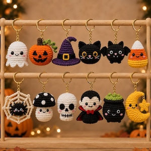 Peut inclure: Une collection de douze porte-clés crochetés sur le thème d'Halloween suspendus à un support en bois. Les figurines incluent un fantôme blanc, une citrouille orange, un chapeau de sorcière violet, un chat noir, une chauve-souris, un bonbon, une toile d'araignée, un champignon, un crâne, un vampire, un chaudron et une lune.