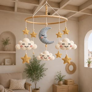 May include: A hanging nursery mobile featuring a circular wooden frame with crocheted elements suspended by white strings. The mobile includes a blue crescent moon, three cream-colored clouds with smiling faces, and six yellow crocheted stars.