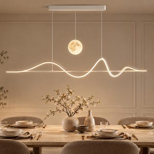 Op de afbeelding: Een lineaire witte LED-hanglamp met een doorlopend golvend ontwerp en een enkele bolvormige maanvormige lamp die aan een rechthoekige plafondbevestiging hangt en een zachte warme gloed over een eettafel verspreidt.