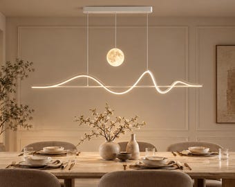 May include: A linear white LED pendant light fixture featuring a continuous wave-like design and a single spherical moon-shaped light suspended from a rectangular ceiling mount, emitting a soft warm glow over a dining table setting.