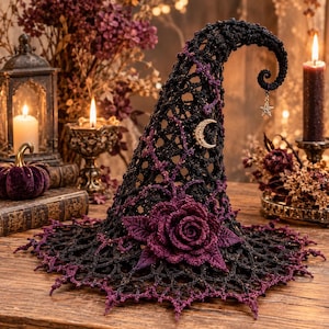 May include: A black crocheted witch hat featuring a pointed, curved top, a wide scalloped brim, and a deep purple rose embellishment at the base. The hat is decorated with a small gold crescent moon charm and a dangling silver star charm.
