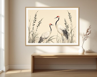 May include: A framed wall art print featuring two white cranes with black wing tips and red crowns standing among tall, slender grasses. The illustration is set against a light cream background, enclosed in a simple light wood frame.