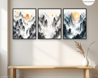 Op de afbeelding: Een set van drie ingelijste wandkunstprints met zwart-witte inktlandschappen, watervallen en een gloeiende oranje zon. De kunstwerken tonen mistige bergtoppen, verspreide bomen en stromend water in een verticale oriëntatie.