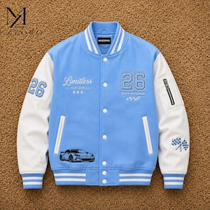 Könnte beinhalten: Eine hellblaue Collegejacke mit weißen Ärmeln, verziert mit dem Schriftzug Limitless EST 2028, der Zahl 26 und dem Text BUILT DIFFERENT. Sie verfügt über ein Autografik-Motiv, Zielflaggen, eine Reißverschlusstasche am Ärmel und gestreifte Bündchen.