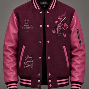 Może przedstawiać: Bordowo-różowa kurtka typu varsity z grafiką rewolweru i róży na piersi. Tekst głosi NOT JUST CLOTHES A MINDSET oraz Chaos Creates Clarity. Kurtka posiada różowe skórzane rękawy, zapięcie na zatrzaski oraz wykończenia w paski na mankietach i dole.