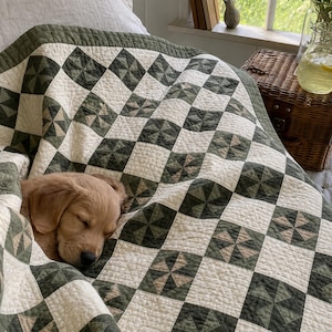 May include: A quilted blanket featuring a repeating pattern of cream and dark olive green squares. Each green square contains a pinwheel design composed of smaller triangles in varying shades of olive and tan. A golden puppy is sleeping under the quilt.