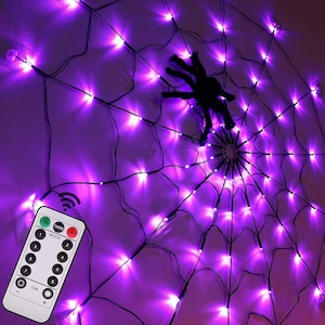 May include: A spider web shaped string light display featuring bright purple LED bulbs arranged in a radial pattern. A black spider figure is positioned near the center of the web. A white remote control with buttons for mode, timer, and dimming is included.