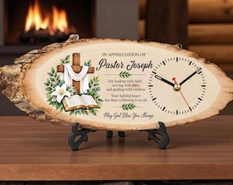 May include: A live edge wood slice clock featuring a printed graphic of a wooden cross draped in white cloth, an open book, and green leaves. The text reads: IN APPRECIATION OF Pastor Joseph, For leading with faith, serving with love, and guiding with wisdom. Your faithful heart has been a blessing to us all. May God Bless You Always.