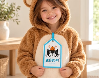 May include: A brown plush bear costume with a hood featuring rounded ears and a cream-colored belly panel. A white rectangular tag with a blue border hangs from the neck, displaying a black cat graphic and the text Jellycat London.