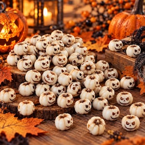 Può includere: Una vasta collezione di piccole perline a forma di zucca color bianco sporco, ognuna caratterizzata da un volto di zucca intagliato dai toni scuri con occhi distinti e una bocca frastagliata, sparse su una superficie di legno.