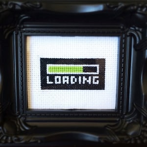 May include: A black framed picture with a white background and a green and black loading bar with the word "LOADING" underneath.