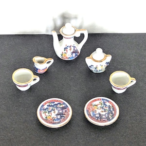 May include: A miniature porcelain tea set with a white base and colorful Asian-inspired designs. The set includes a teapot, sugar bowl, creamer, two teacups, and two saucers. Each piece has gold trim and intricate floral and architectural patterns.