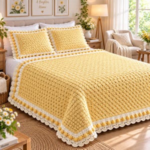 May include: A yellow crochet bedspread and two matching pillow shams featuring a textured diamond pattern. The set is bordered by a white crocheted trim with small yellow pom-poms along the edges, creating a decorative finish for the bedding.
