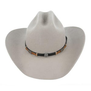 Op de afbeelding: Een lichtgrijze cowboyhoed met een cattleman-vouw in de kroon en een brede rand. De hoed is voorzien van een zwarte leren hoedband met afwisselend rechthoekige bruine en zilverkleurige metalen plaatjes en een centrale ronde zilverkleurige concho.