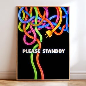May include: A framed wall art print featuring a black background with glowing, neon-coloured tangled electrical cords in blue, green, orange, and pink. An orange electrical plug is visible, and the text PLEASE STANDBY is printed in white.
