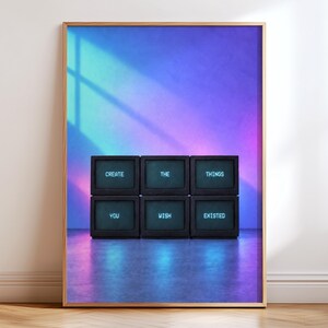 May include: A framed vertical wall art print featuring six stacked black television monitors against a vibrant blue and purple gradient background. Each screen displays a single word in white text, reading: CREATE THE THINGS YOU WISH EXISTED.