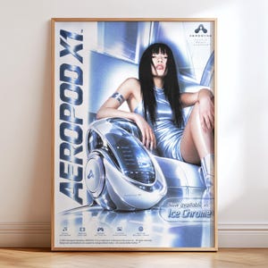 Peut inclure: Une affiche publicitaire encadrée pour l'Aeropod X1 montrant une personne aux longs cheveux noirs en robe bleue métallique assise à côté d'un appareil multimédia chromé futuriste. Le texte indique Aeropod X1 et Now available in Ice Chrome.