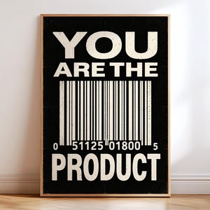 Könnte beinhalten: Ein rechteckiger Wandkunstdruck in einem hellen Holzrahmen mit schwarzem Hintergrund und weißem Text, der YOU ARE THE PRODUCT lautet. Eine große weiße Strichcode-Grafik ist zwischen den beiden Textzeilen zentriert, mit den Zahlen 0 51125 01800 5.