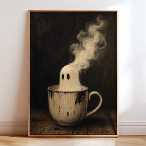 Op de afbeelding: Een ingelijste muurkunstprint met een witte spookfiguur die uit een gespikkelde, gebroken witte keramische mok komt. Het spook heeft twee donkere ovale ogen en wazige, rookachtige slierten die opstijgen tegen een donkere, getextureerde achtergrond.