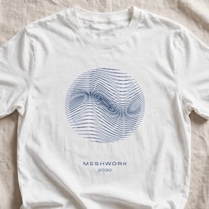 May include: A white short-sleeved t-shirt featuring a circular graphic composed of dark blue wavy lines in the center. Below the graphic, the text MESHWORK 2030 is printed in a dark blue sans-serif font. The shirt has a crew neckline.