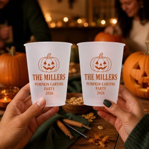 Puede incluir: Dos vasos de plástico esmerilado con un gráfico naranja de una calabaza de Halloween y el texto THE MILLERS PUMPKIN CARVING PARTY 2026. Los vasos tienen un acabado liso y translúcido, mostrados frente a un fondo de calabazas y decoración.