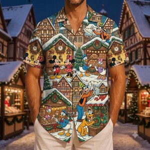 Puede incluir: Una camisa de manga corta con botones y un estampado colorido de personajes de Disney, incluyendo a Mickey Mouse, Minnie Mouse, el Pato Donald, Daisy, Goofy y Pluto en un pueblo nevado con puestos de mercado navideño.
