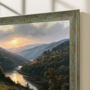 Può includere: Un dipinto di paesaggio in una cornice verde salvia usurata raffigura un fiume che serpeggia attraverso una valle al tramonto. La scena presenta colline coperte di alberi, nuvole soffici e un sole luminoso che riflette l'oro sull'acqua.