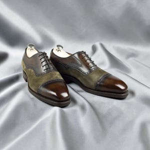 Peut inclure: Une paire de chaussures oxford bicolores avec des bouts et des contreforts en cuir poli marron foncé, contrastés par des panneaux latéraux en daim vert olive. Ces chaussures à lacets présentent des détails brogues le long des coutures.