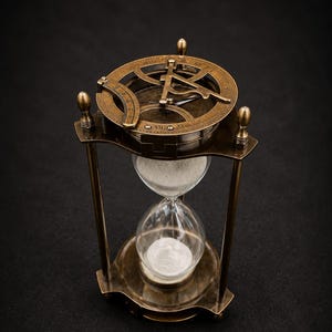 Peut inclure: Un sablier en laiton de style ancien avec un bulbe en verre transparent rempli de sable blanc. Le haut du cadre est intégré à un cadran solaire circulaire en laiton comprenant des chiffres romains gravés et un pointeur gnomon central.