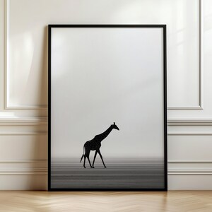 May include: A framed wall art print featuring a black silhouette of a giraffe walking across a horizontal landscape against a light gray, misty background. The artwork is enclosed in a thin black frame, creating a high-contrast, monochromatic visual.