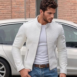 May include: A white jacket with a textured crocodile skin pattern, featuring a stand-up collar, a full-length silver zipper, and two side pockets with silver zippers, worn over a plain white t-shirt and blue denim jeans with a brown leather belt.