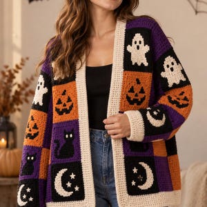 Peut inclure: Un cardigan en crochet à manches longues avec un motif patchwork composé de fantômes blancs, de citrouilles orange, de chats noirs et de croissants de lune blancs sur des carrés violets, orange et noirs, bordé d'une bordure couleur crème.