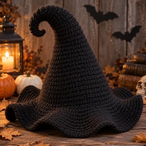 Puede incluir: Un sombrero negro de ganchillo con un ala ancha y ondulada y una corona alta y puntiaguda que se curva en la parte superior. El sombrero está hecho con un punto de hilo denso y texturizado, creando un aspecto oscuro y sólido con una forma flexible.