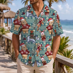 Könnte beinhalten: Ein kurzärmeliges Hemd mit Knopfleiste in Blaugrün mit einem wiederkehrenden weihnachtlichen Muster aus Winnie Puuh, Ferkel und I-Aah, die festliche Pullover und Weihnachtsmützen tragen, durchsetzt mit Tannenbäumen und Schneeflocken.