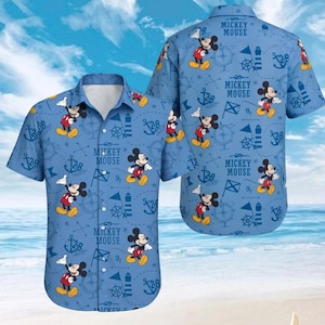 May include: A light blue short-sleeve button-down shirt featuring an all-over print of Mickey Mouse, lighthouses, anchors, and nautical compasses. The text "Mickey Mouse" is printed in dark blue throughout the pattern on the front and back.