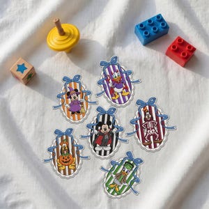 May include: Six oval-shaped stickers featuring Disney characters in Halloween costumes, including Mickey Mouse as a vampire, Minnie Mouse as a witch, Donald Duck as a devil, Daisy Duck as Frankenstein, Goofy as a skeleton, and Pluto as a pumpkin.