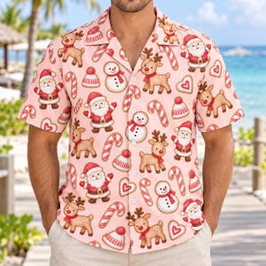 Puede incluir: Una camisa de manga corta con botones en color rosa claro con un patrón navideño repetitivo. El estampado incluye ilustraciones de Santa Claus, renos, muñecos de nieve, bastones de caramelo, gorros de invierno y galletas en forma de corazón.