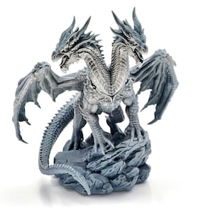 May include: A gray two-headed dragon figurine standing on a rocky base. The creature features detailed scales, large spread wings, sharp horns on both heads, and a long, curved tail. The dragon is depicted in a standing position with claws.