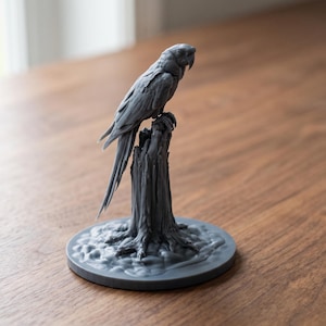 May include: A monochromatic gray 3D printed figurine of a parrot perched atop a textured tree stump. The bird features detailed plumage and a curved beak, while the base is circular with a rugged, uneven surface texture resembling forest ground.