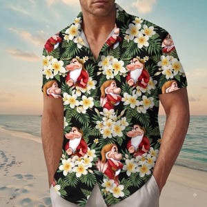 Pode incluir: Uma camisa de manga curta com botões, apresentando um fundo preto com um padrão repetitivo de flores de plumeria brancas e amarelas, folhas de samambaia verdes e um personagem de desenho animado com barba branca e túnica vermelha.