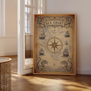 May include: A rectangular wall art print titled SEA CHART featuring a vintage-style map with a central compass rose, illustrations of four sailing ships, and two sea dragons at the bottom, all framed in a light-coloured wooden frame.