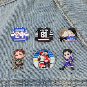 Peut inclure: Six épinglettes en émail sur le thème du hockey. Un maillot bleu avec HOLLANDER 24, un maillot noir avec ROZANOV 81, deux épinglettes montrant des paires de joueurs de hockey et deux joueurs individuels en maillot, le tout dans un style cartoon.